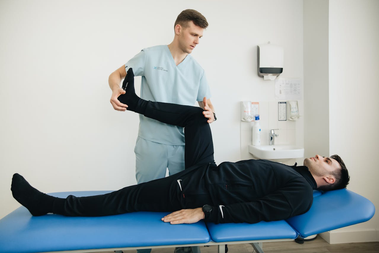 A patient performing a leg exercise under the guidance of a physiotherapist in a clinical Pilates session.