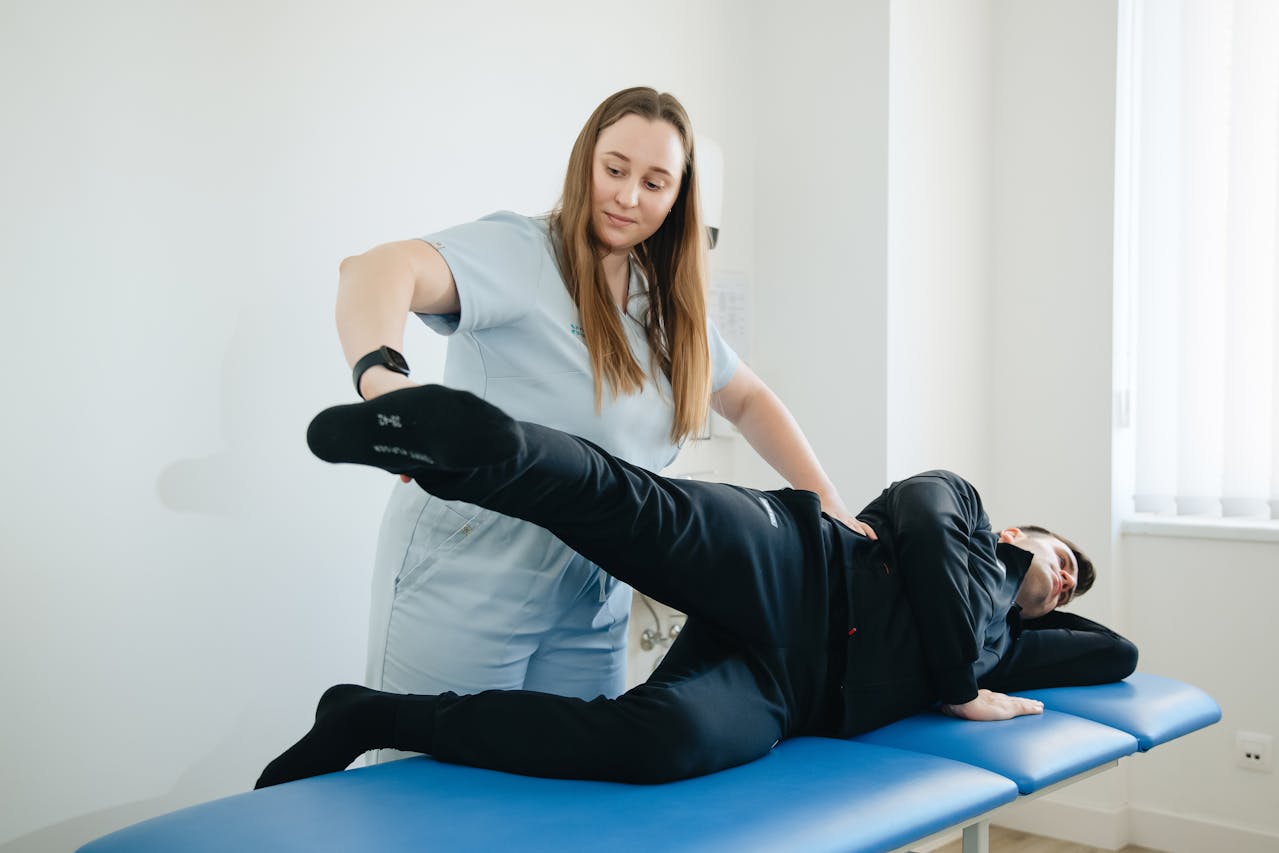 A physiotherapist assisting a patient with a side-lying leg exercise for rehabilitation.